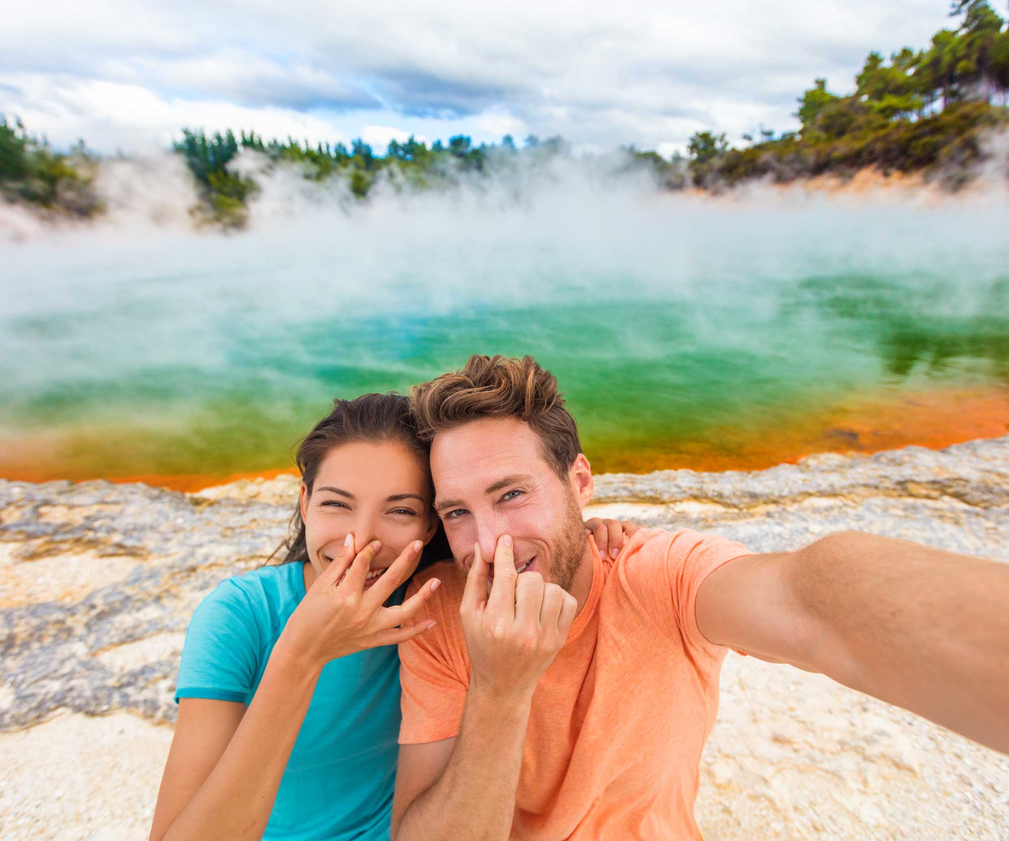 couple holding noses in front of hot pools